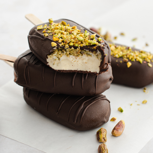 Barre glacée maison à la pistache enrobée de chocolat noir, garnie de pistaches concassées croquantes.