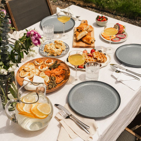 Table de brunch maison avec croissants, bouchées, fruits frais et boissons, parfait pour un repas gourmand du week-end